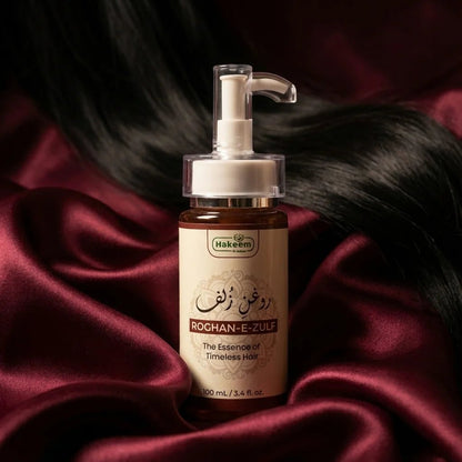 Bottle of Hakeem Roghan-E-Zulf hair product on a dark fabric background