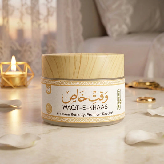 A cosmetic jar labeled WAQT-E-KHAAS Premium sits on a marble surface with a lit candle and soft home decor in the background. The product has a light wood-grain lid and a cream label with gold and black text.